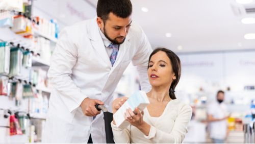 Preparing for accessible travel: Woman in wheelchair asking a pharmacist about medication.